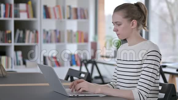 图书馆有头痛的年轻女子使用手提电脑视频的预览图