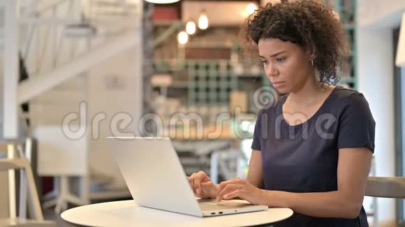 年轻的非洲妇女在咖啡厅的笔记本电脑上感到震惊视频的预览图