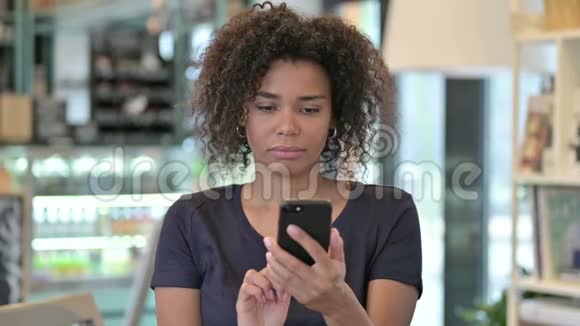 青年非洲妇女在智能手机上的损失画像视频的预览图