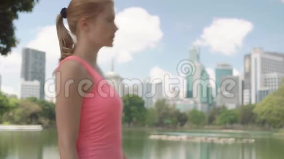 美丽的女跑步者在公园慢跑适合女性运动健身训练休息一下伸展一下视频的预览图