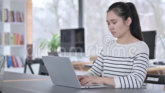 年轻的亚洲妇女背部疼痛使用笔记本电脑视频的预览图