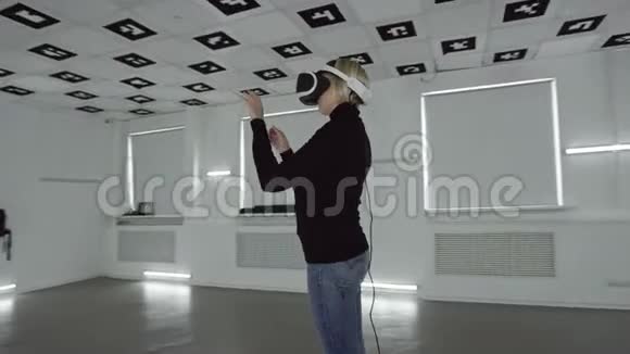 年轻女子戴着vr耳机在一个充满白色霓虹灯的空房间里做手势追踪弧射视频的预览图