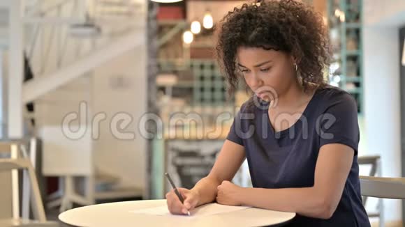 体贴的非洲青年妇女在咖啡厅做文书工作视频的预览图