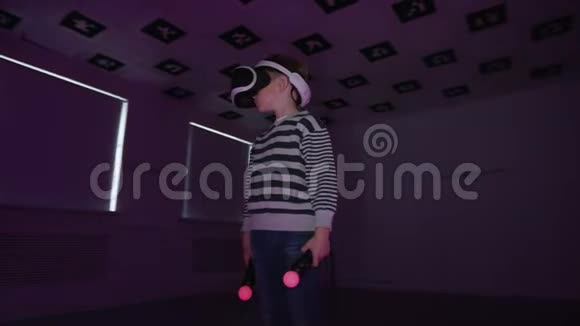 小男孩在虚拟现实中环顾四周拿着控制器戴着耳机房间里闪烁着红色视频的预览图