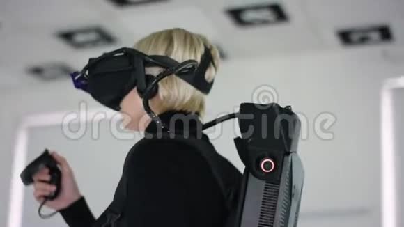 在一个充满白光的空玩室里一位戴着vr耳机的成年女子手持控制器的特写镜头跟踪视频的预览图