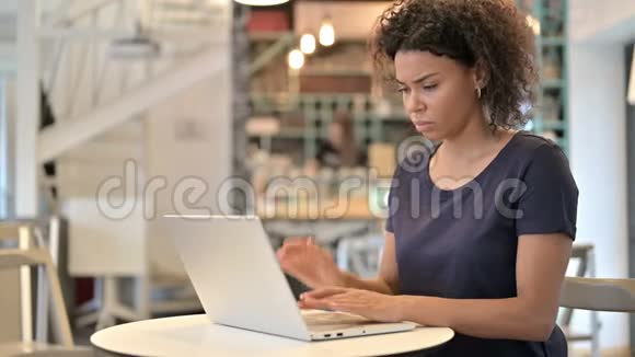 有头痛的非洲青年妇女在咖啡厅使用笔记本电脑视频的预览图