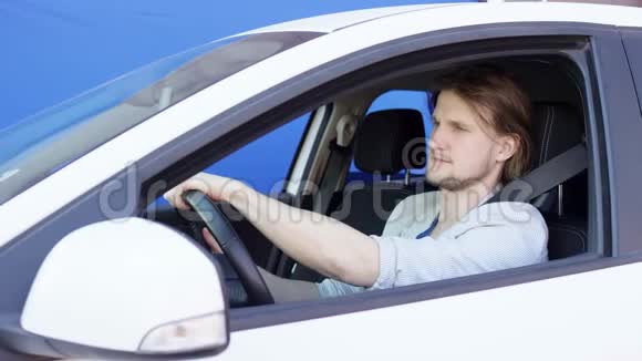 有趣的家伙开着车自拍穿着T恤和夹克的布鲁内特男子正坐在蓝色的汽车上视频的预览图