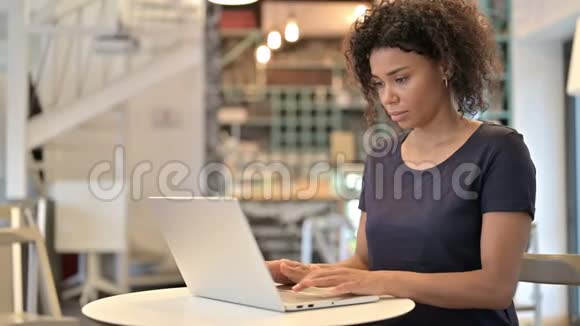 青年非洲妇女在咖啡厅手提电脑庆祝成功视频的预览图