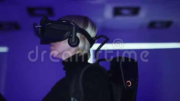 一位成年女性的特写镜头正在虚拟现实耳机中玩视频游戏并使用控制器空玩室视频的预览图