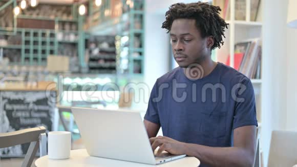 有笔记本电脑的非洲男人在咖啡馆里对着镜头微笑视频的预览图