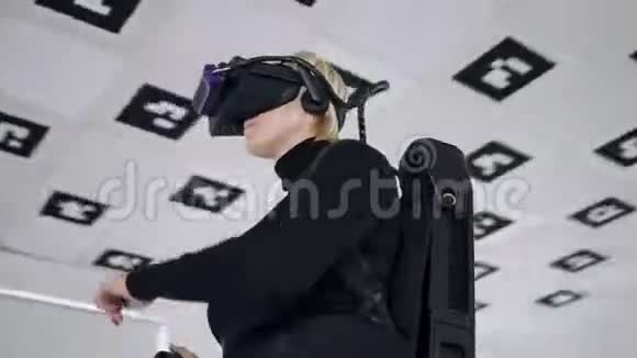 成年女性在虚拟现实耳机里玩跳舞的视频游戏同时在一个大空的游戏室里拿着控制器视频的预览图