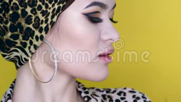一个漂亮的年轻女人穿着一件用黄色豹纹织物做成的时髦头巾视频的预览图
