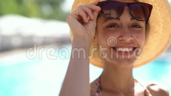 戴着帽子戴着太阳镜的白种人快乐的女人手里拿着相机微笑视频的预览图