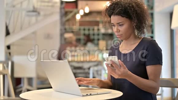 在咖啡厅使用笔记本电脑和智能手机的年轻非洲妇女视频的预览图