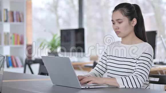 办公室颈部疼痛的年轻亚洲妇女使用笔记本电脑视频的预览图