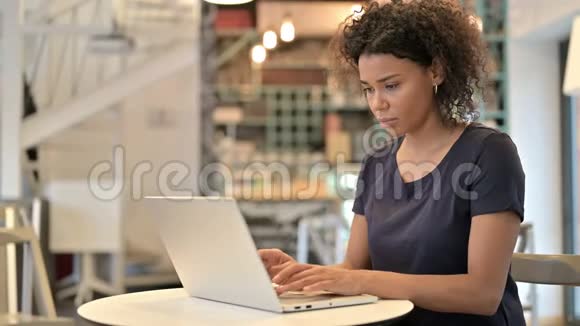 青年非洲妇女在咖啡馆里看相机的笔记本电脑使用视频的预览图