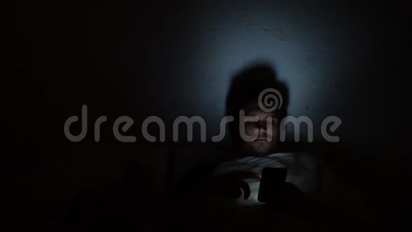 晚上躺在床上的年轻人使用智能手机失眠和数字依赖躺在床上的女孩视频的预览图