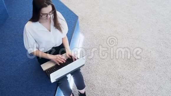 年轻的女学生使用笔记本电脑一个年轻的黑发女人坐在键盘上打字视频的预览图