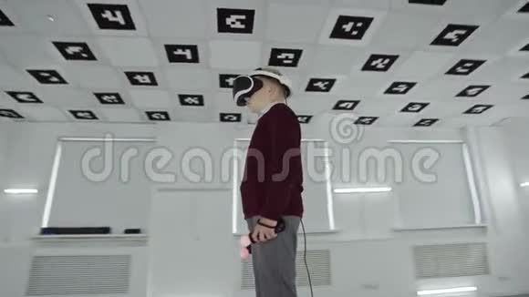 一个穿着棕色毛衣的小男孩站在虚拟现实耳机里手里拿着控制器里面装满了空玩室视频的预览图