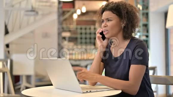 年轻的非洲妇女在咖啡馆的智能手机上愤怒视频的预览图