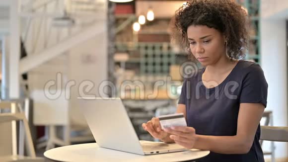 非洲女青年在笔记本电脑上成功在线支付咖啡厅视频的预览图