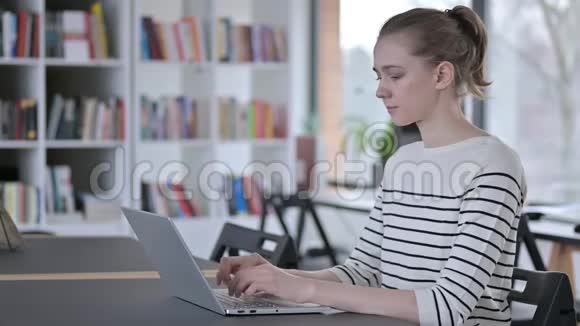 青年妇女在图书馆看相机使用笔记本电脑视频的预览图