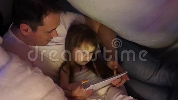 家庭圣诞节的概念孩子和爸爸在圣诞节晚上玩平板电脑在儿童房在帐篷里视频的预览图