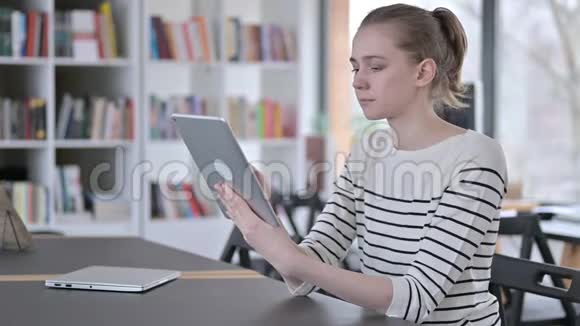 图书馆美丽青年妇女使用数码平板电脑视频的预览图