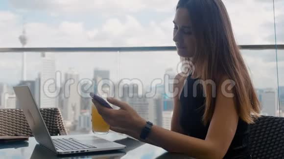 一个商人坐在一家餐馆里手提电脑点击电话喝4K果汁视频的预览图