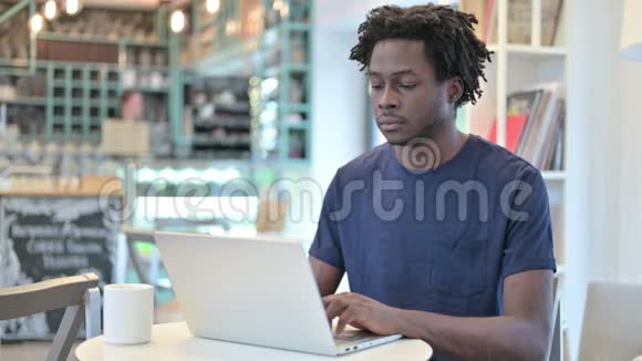 有笔记本电脑的非洲男人在咖啡厅看镜头视频的预览图