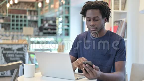 在咖啡厅使用智能手机和笔记本电脑的非洲男子视频的预览图