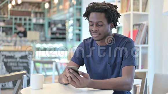 非洲男子在咖啡厅使用智能手机视频的预览图