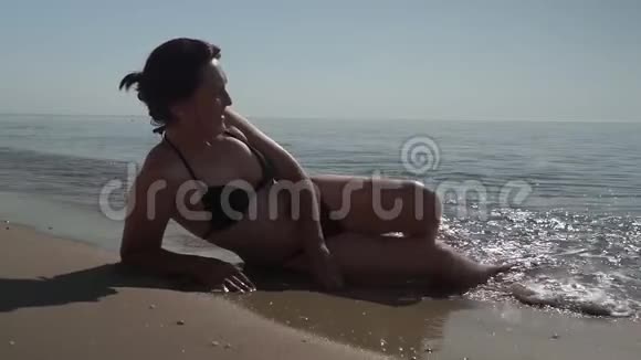 年轻女孩躺在海边和日光浴无法辨认的女人在暑假旅行时在海边放松视频的预览图