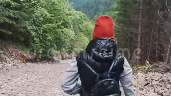 戴橙色帽子的女孩扔石头秋天在森林里散步的美丽的小女孩把石头扔进了森林视频的预览图