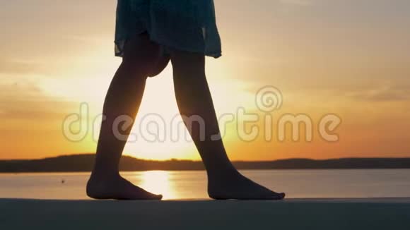 在夕阳下闪烁的沙滩上女子双脚的特写视频的预览图