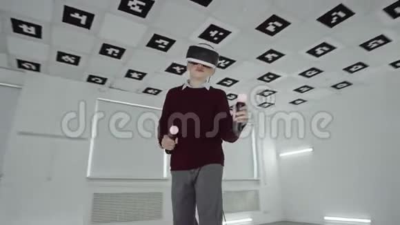 穿着棕色毛衣的小男孩正在玩虚拟现实耳机中的视频游戏并在空的时候使用控制器视频的预览图