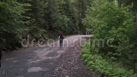 一个背着背包的女人正沿着山路走美丽的山脉背景上的女孩前往视频的预览图