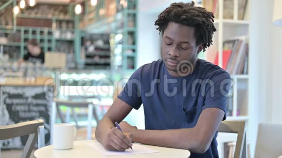 体贴的非洲男人在咖啡厅做文书工作视频的预览图