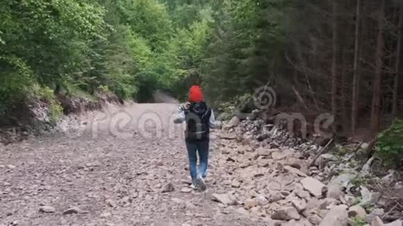 一个背着背包的女人正沿着山路走美丽的山脉背景上的女孩前往视频的预览图