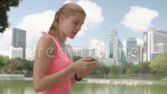 美丽的女跑步者在公园慢跑适合女性运动健身训练在她的智能手机上聊天视频的预览图