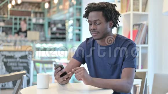 在咖啡馆里讲智能电话的非洲男人视频的预览图