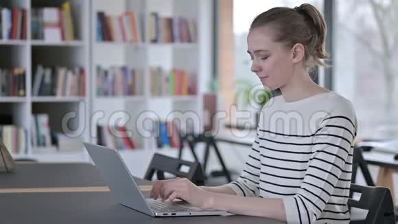 青年妇女使用图书馆笔记本电脑竖起大拇指视频的预览图