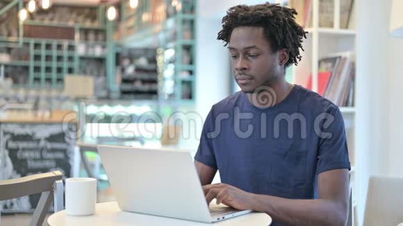 咖啡屋里拿着笔记本电脑的非洲男人竖起的大拇指视频的预览图