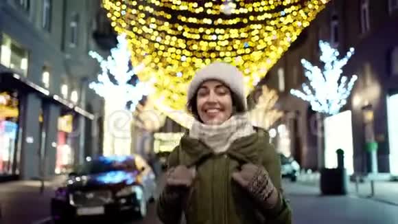 快乐的笑着年轻的女人穿着温暖的冬衣快速的嬉戏走着夜城街视频的预览图