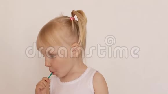 三岁的白种人小女孩扎着小辫子舔着糖果棒视频的预览图