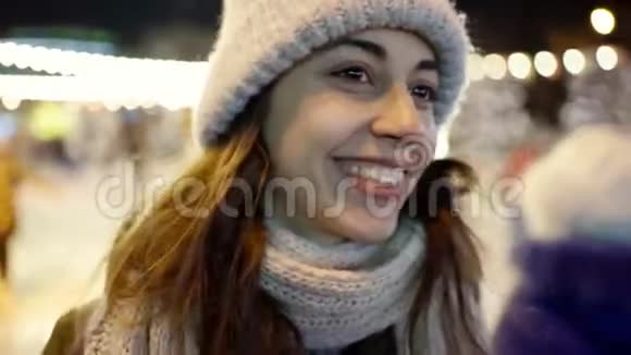 幸福微笑的年轻女子穿着温暖的冬衣站在城市溜冰场背景上的特写肖像视频的预览图
