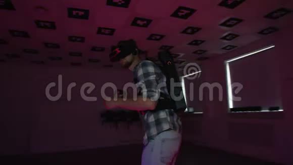 虚拟现实耳机里的年轻人正在一个充满红色和蓝色霓虹灯闪烁的空玩室里玩虚拟现实游戏视频的预览图