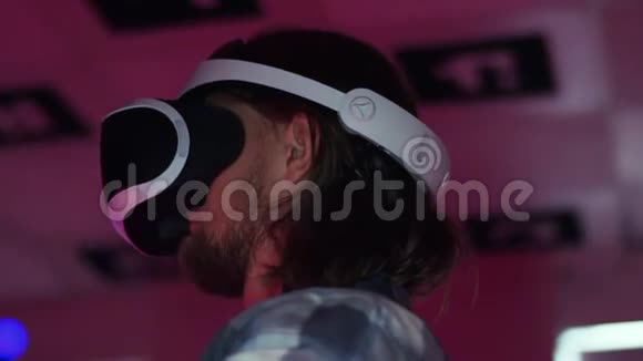 近距离追踪一个年轻人戴着虚拟现实耳机用控制器举起双手的360度摄影镜头视频的预览图