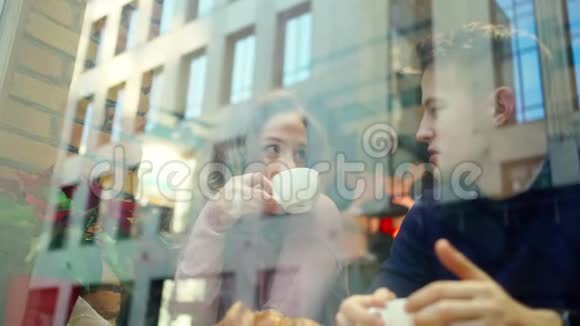 年轻漂亮的夫妇在舒适的咖啡馆里约会聊天喝咖啡一起玩视频的预览图