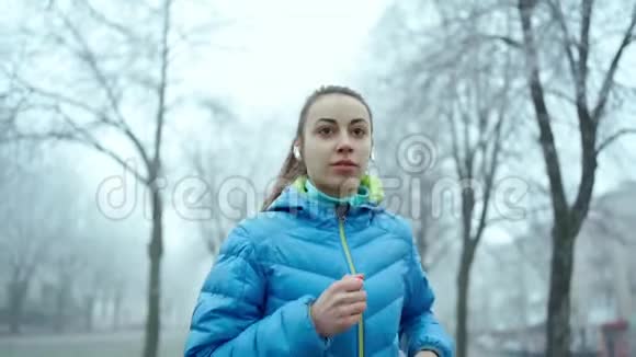 慢动作的年轻运动的女人用无线耳机跑步视频的预览图